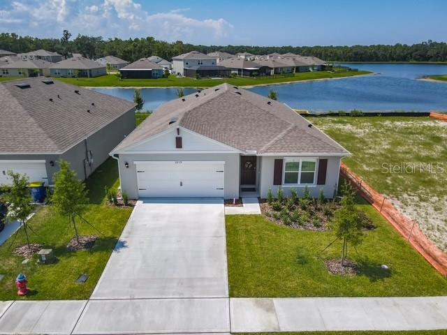 An aerial view shows a single-story house with a two-car garage near a lake — 2219 LAKE PRESERVE CIRCLE, NEW SMYRNA BEACH, FL