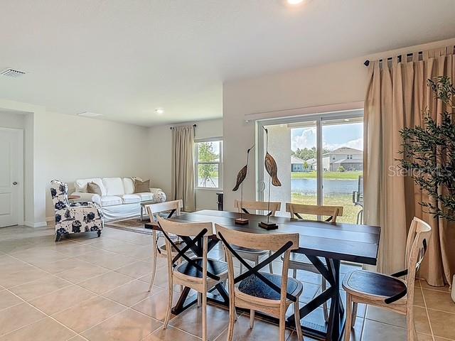 A dining area with a wooden table and chairs sits adjacent to a living room — 2219 LAKE PRESERVE CIRCLE, NEW SMYRNA BEACH, FL