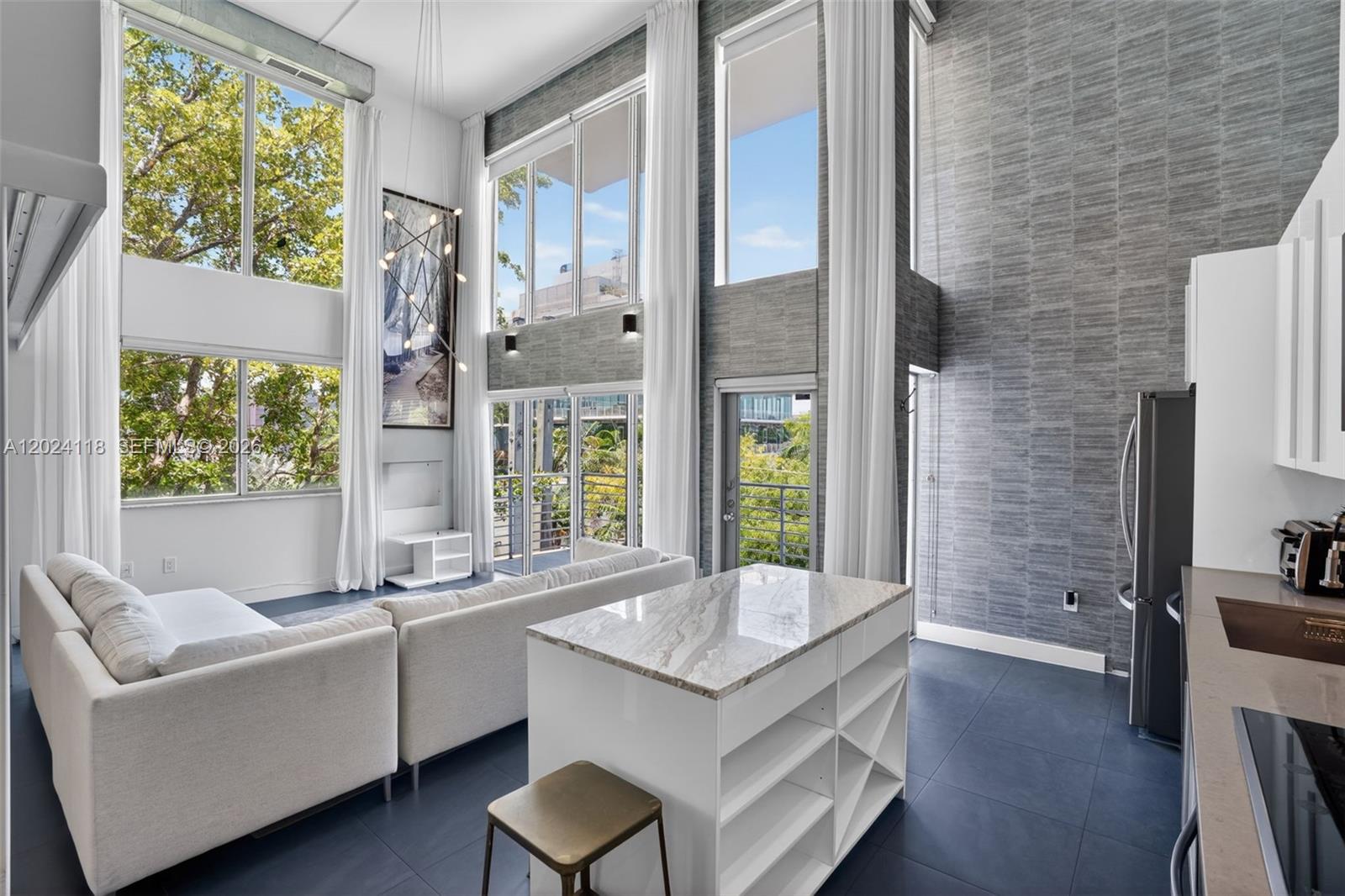 A modern living room and kitchen area with double-height ceilings, floor-to-ceiling windows, and gray wallpaper — 900 4th St # 6, Miami Beach FL 33139, MIAMI BEACH, FL