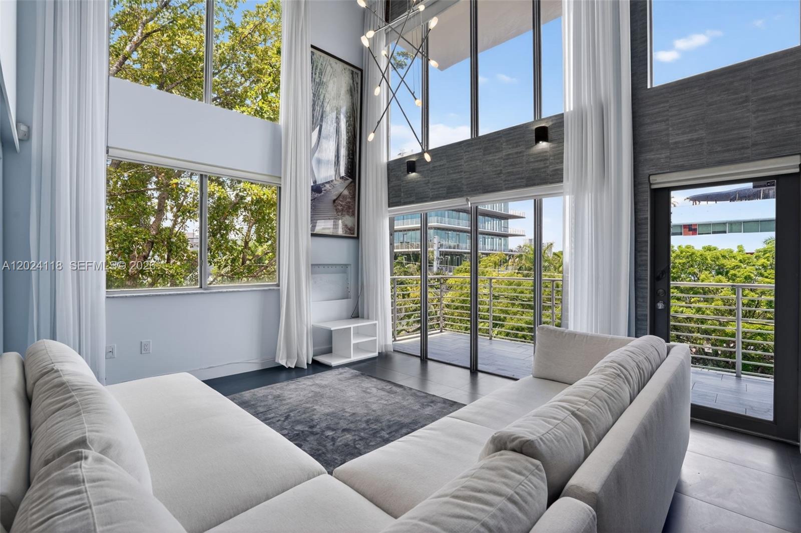 A modern living room features double-height windows, a large sectional sofa, and a balcony view — 900 4th St # 6, Miami Beach FL 33139, MIAMI BEACH, FL