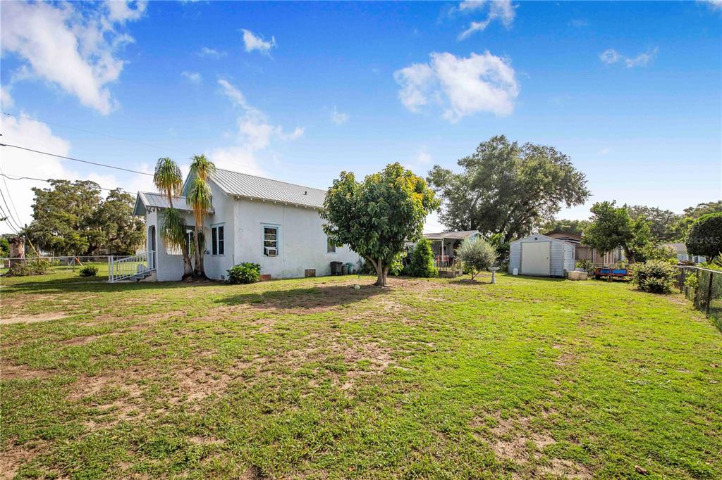 A white house with a metal roof sits on a large, grassy lot with trees — 229 N 13TH STREET, HAINES CITY, FL