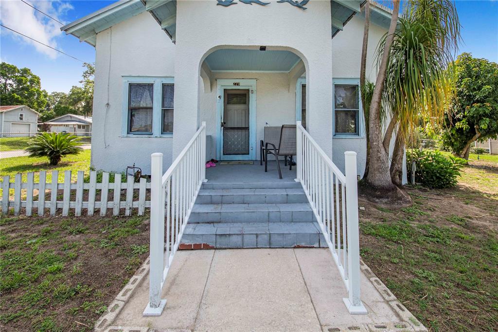 A white house with a blue-trimmed porch, stairs, and a white railing in the front — 229 N 13TH STREET, HAINES CITY, FL