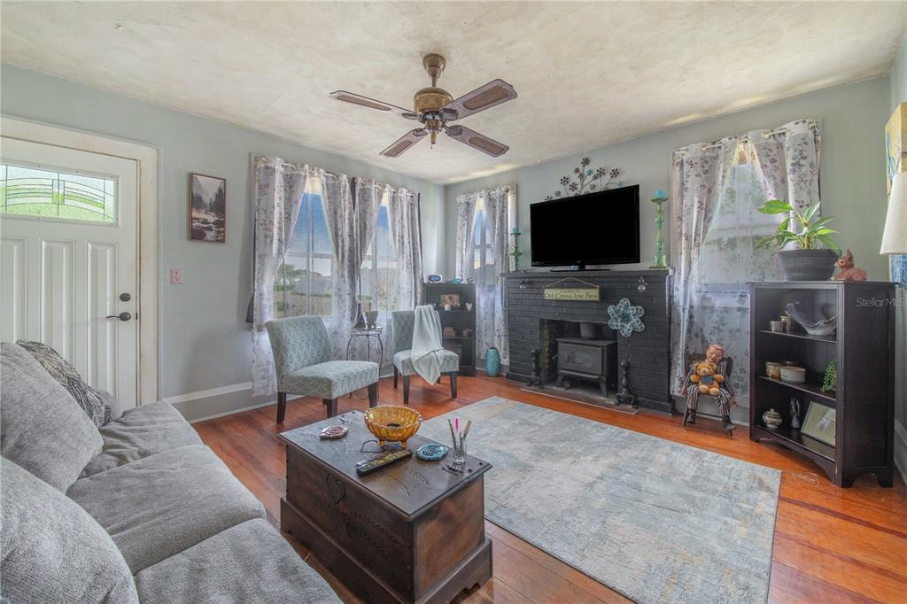 A living room features a black brick fireplace, hardwood floors, and a ceiling fan — 229 N 13TH STREET, HAINES CITY, FL