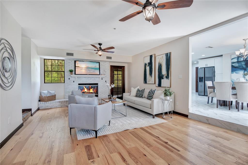 A living room with light wood floors, a white brick fireplace, and an adjacent dining area — 1898 ODHAM DRIVE, DELTONA, FL