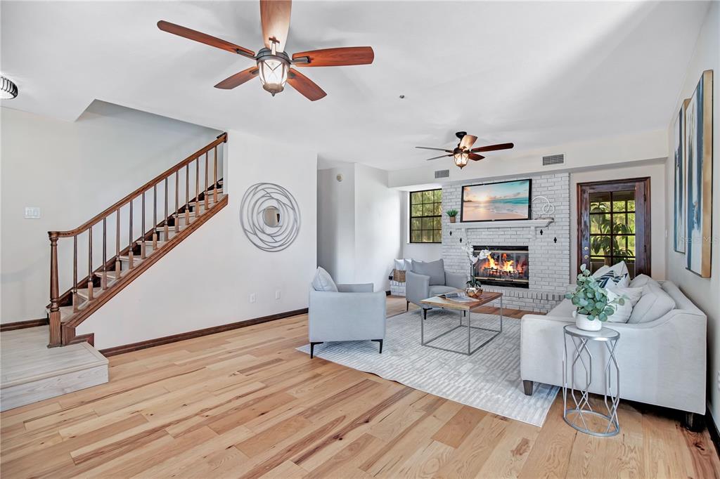A living room features light wood floors, a brick fireplace, a staircase, and two ceiling fans — 1898 ODHAM DRIVE, DELTONA, FL
