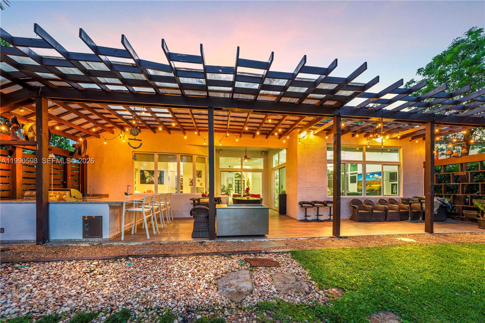 A covered patio features a built-in outdoor kitchen, seating areas, and a wooden pergola — 5265 SW 171st Ave, Miramar FL 33027, MIRAMAR, FL