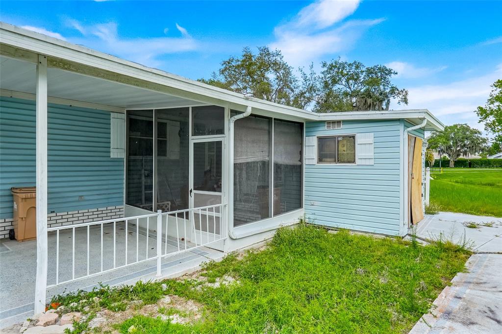 A light blue mobile home features a screened-in porch and an attached storage shed — 25224 WILD HERON, LEESBURG, FL