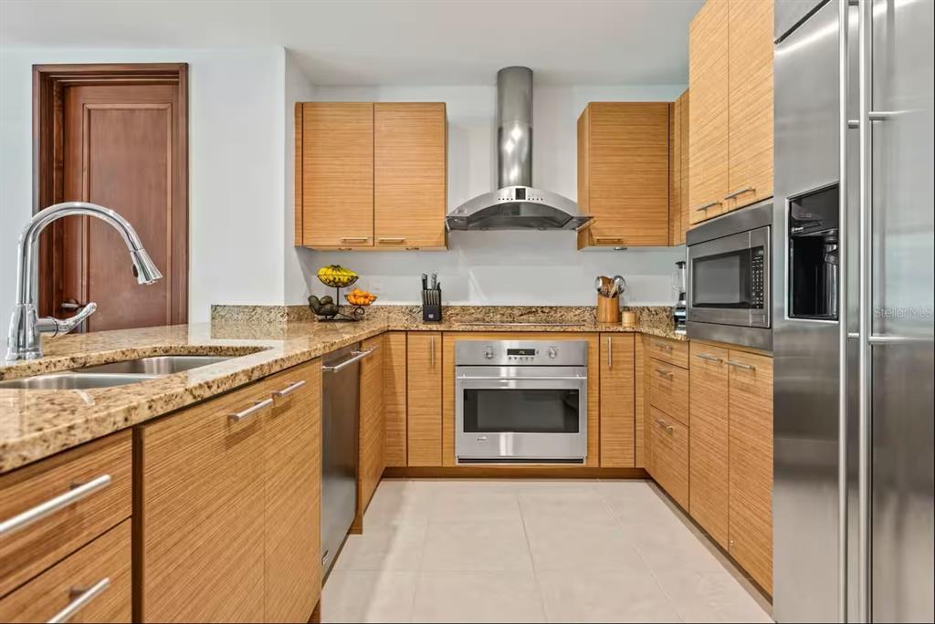A kitchen with light wood cabinets, granite countertops, stainless steel appliances, and tile flooring — 7000 Bahia Beach Blv LAS VERANDAS UNIT 5138, RIO GRANDE, PR