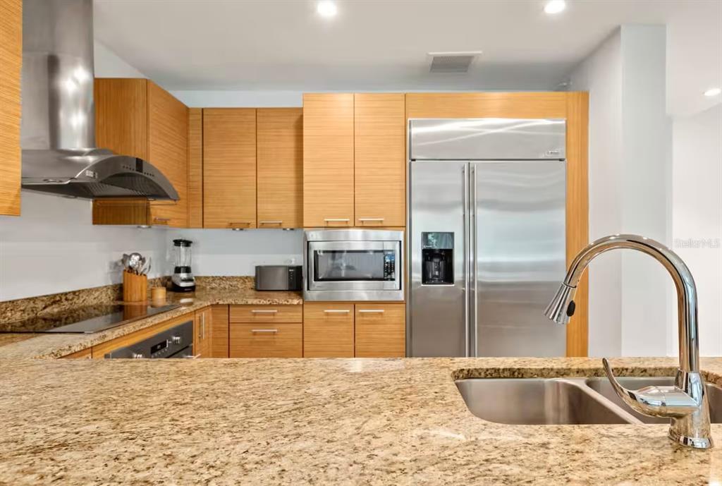 A modern kitchen features light wood cabinets, granite countertops, and stainless steel appliances — 7000 Bahia Beach Blv LAS VERANDAS UNIT 5138, RIO GRANDE, PR