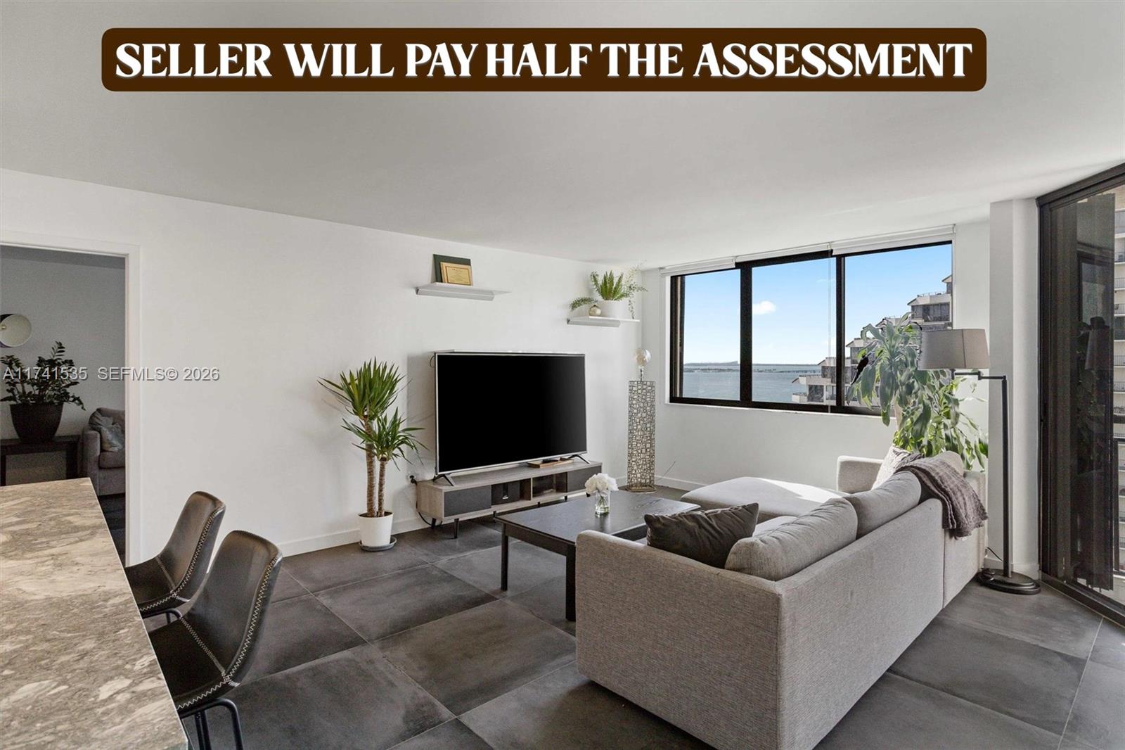 A modern living room features large dark floor tiles, a grey sectional sofa, and water views — 540 Brickell Key Dr # 1519, Miami FL 33131, MIAMI, FL
