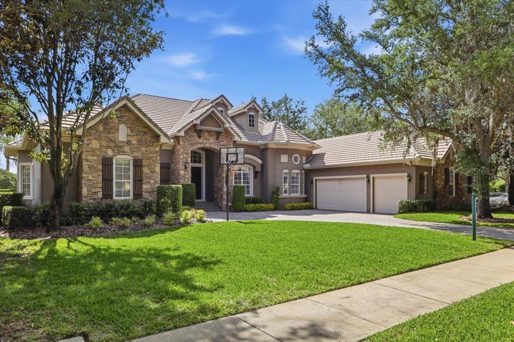 A stone-clad entryway features a double door, arched transom window, and brick steps — 6102 S HAMPSHIRE COURT, WINDERMERE, FL