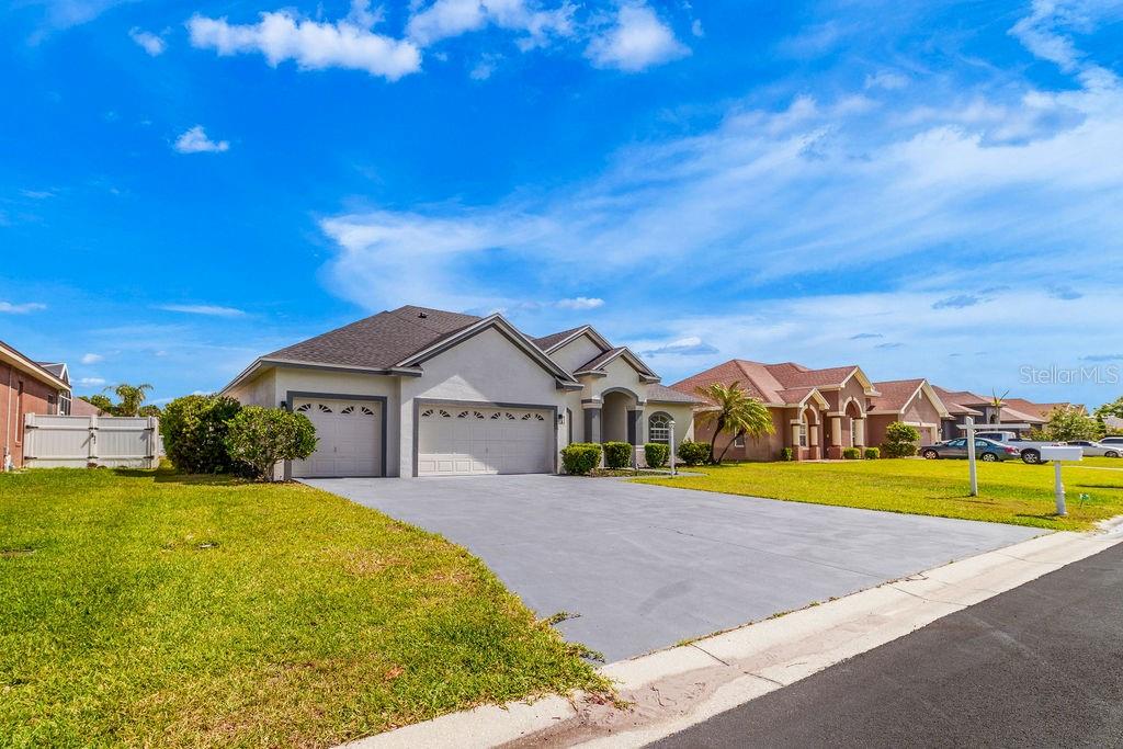 A single-story house with a three-car garage and a paved driveway under a blue sky — 258 TERRANOVA BOULEVARD, WINTER HAVEN, FL