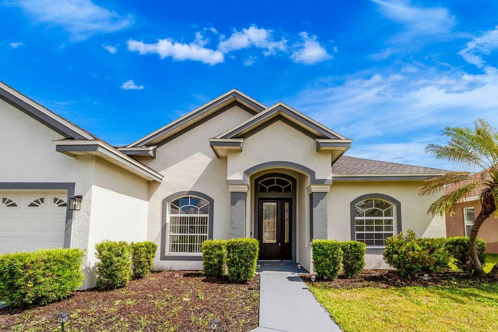 The exterior of a single-story house features a stucco facade, arched windows, and a covered entryway — 258 TERRANOVA BOULEVARD, WINTER HAVEN, FL