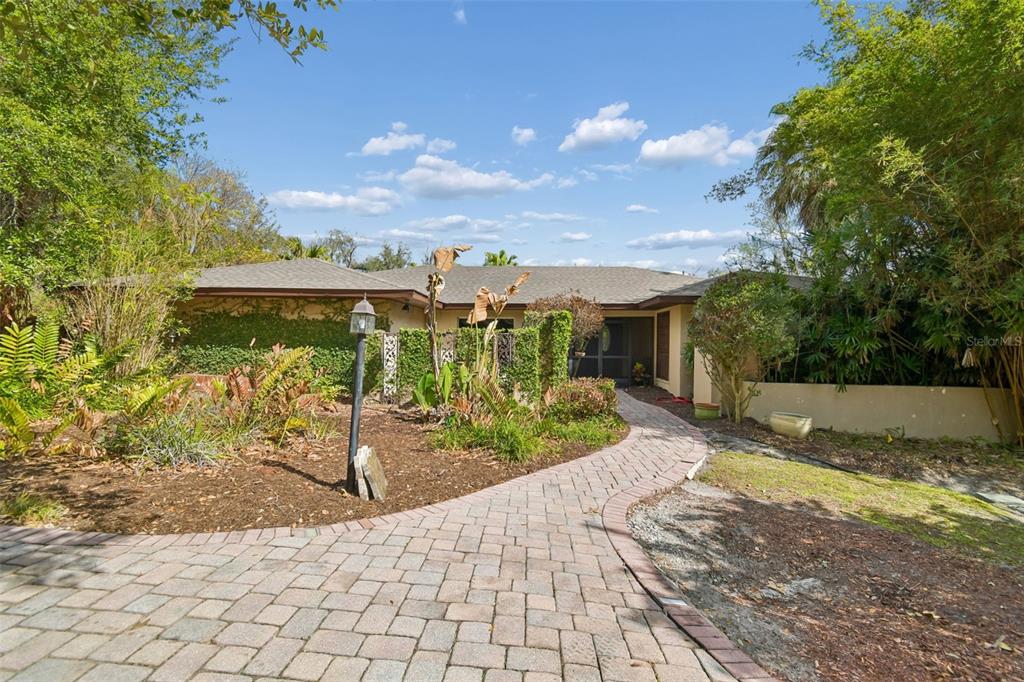 A paved walkway leads to the entrance of a single-story house surrounded by lush landscaping — 5324 WOODHAVEN LANE, LAKELAND, FL