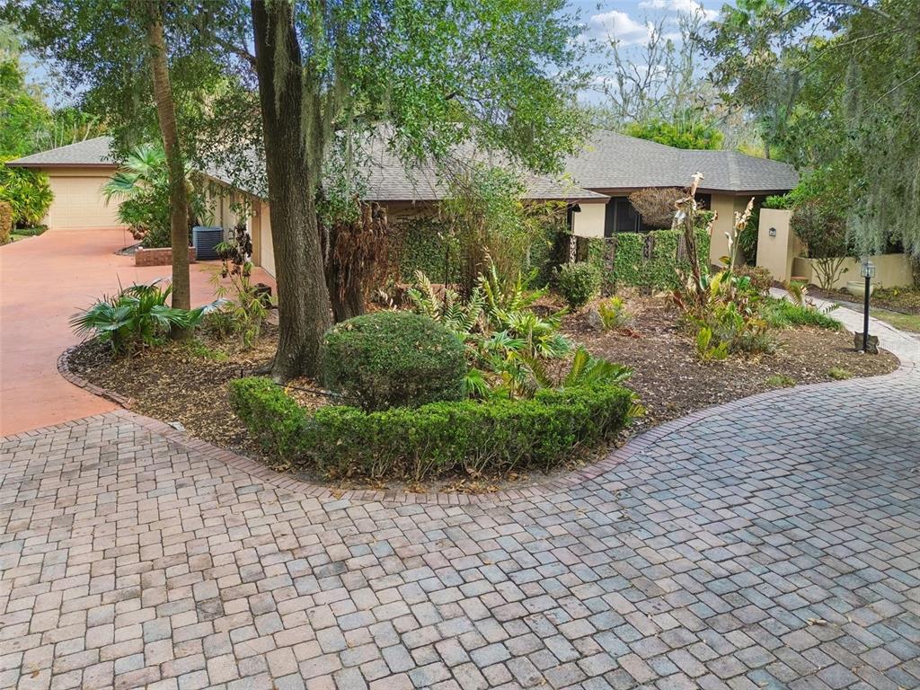 A paved driveway leads to a house with a landscaped front yard and mature trees — 5324 WOODHAVEN LANE, LAKELAND, FL