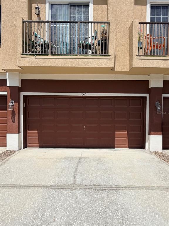 A two-story building exterior featuring a brown garage door and an upper-level balcony — 1521 SAN JACINTO CIRCLE, SANFORD, FL