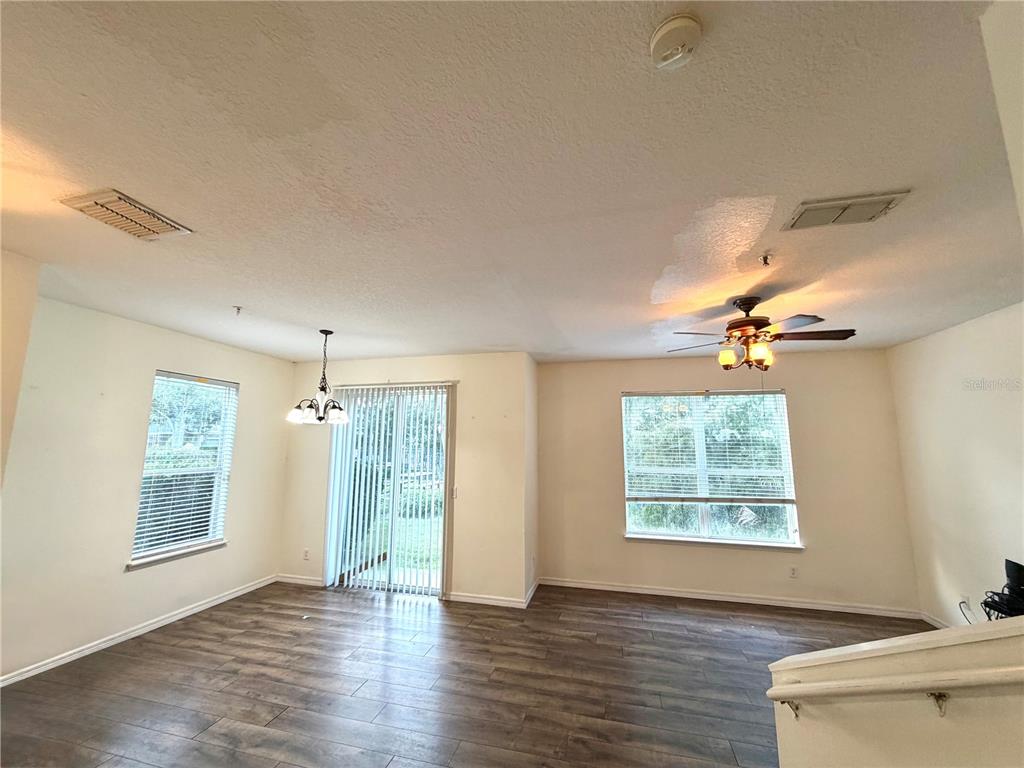 An empty living room features wood-look flooring, a ceiling fan, and a staircase with carpet — 1521 SAN JACINTO CIRCLE, SANFORD, FL