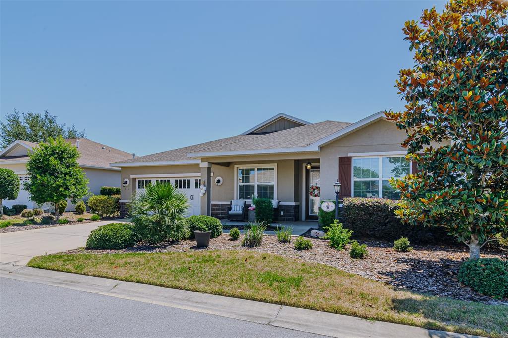 A single-story suburban house with a tan exterior, a garage, and a landscaped front yard — 9985 SW 88TH LOOP, OCALA, FL