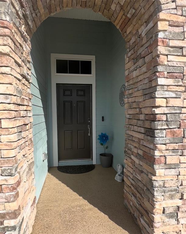 A light blue single-story house features a stone-accented entryway and a three-car garage — 9332 SW 58TH CIRCLE, OCALA, FL