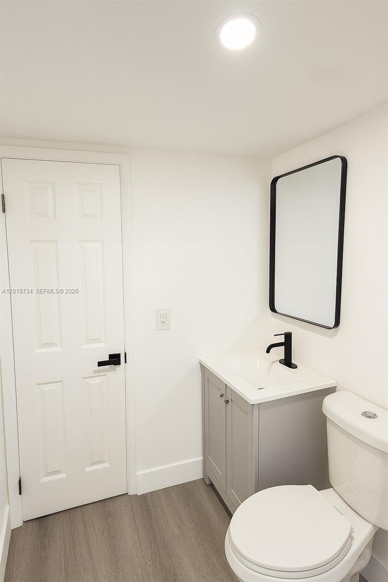 A small bathroom features a grey vanity, a black-framed mirror, and a white toilet — 417 NW 2nd Ave # 9, Hallandale Beach FL 33009, HALLANDALE BEACH, FL