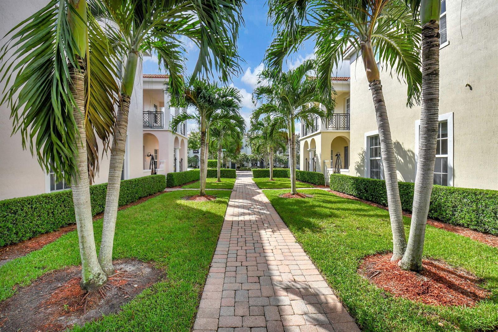 A brick walkway leads between two residential buildings lined with palm trees and manicured hedges — 838 NW 83rd Lane, Boca Raton FL 33487, BOCA RATON, FL