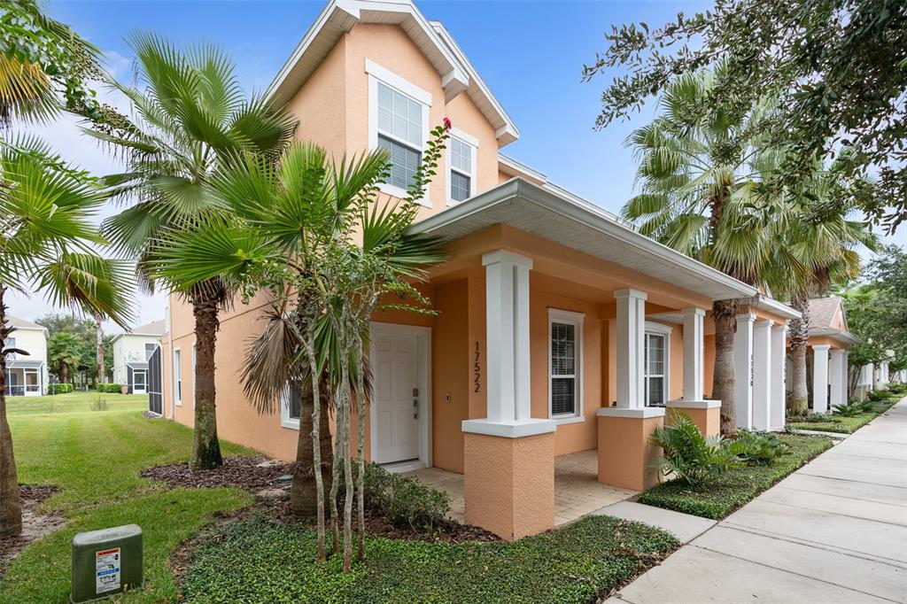 A two-story peach-colored house features a covered front porch with white columns and palm trees — 17522 PLACIDITY AVENUE, CLERMONT, FL