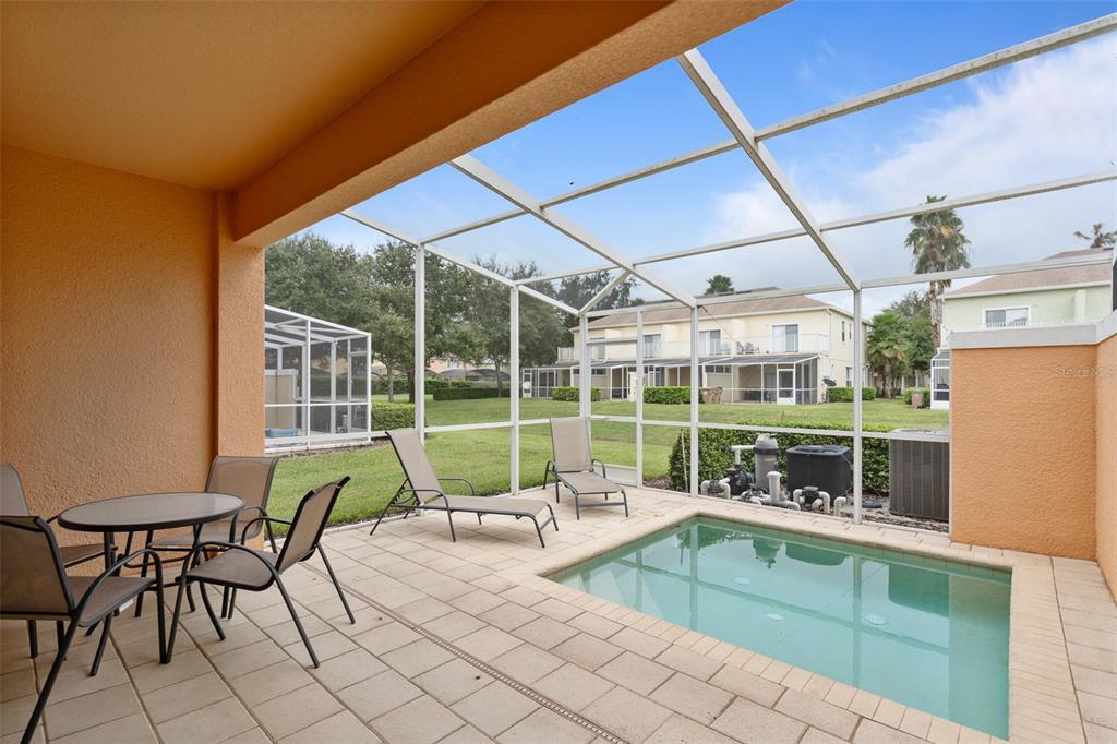 A screened-in patio features a small pool, patio furniture, and views of neighboring townhomes — 17522 PLACIDITY AVENUE, CLERMONT, FL