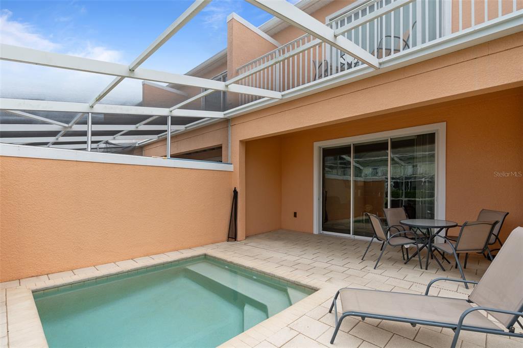 A small swimming pool sits on a paved patio next to a house with sliding doors — 17522 PLACIDITY AVENUE, CLERMONT, FL