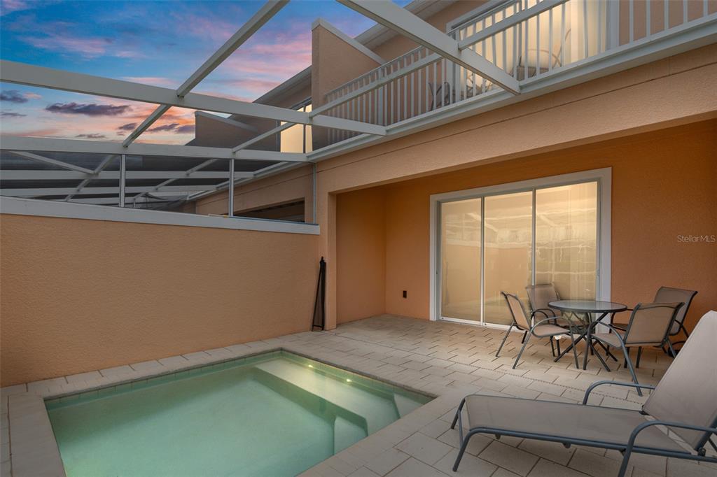 A small rectangular pool sits on a paved patio next to a house with sliding doors — 17522 PLACIDITY AVENUE, CLERMONT, FL