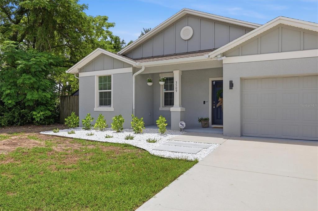 A gray single-story house features a covered porch, white rock landscaping, and a concrete driveway — 3509 E 10TH AVENUE, TAMPA, FL