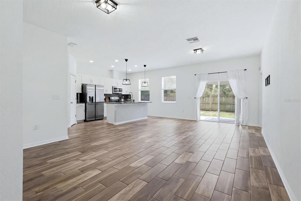 An open-concept kitchen and living area features white cabinets, a kitchen island, and wood-look flooring — 3509 E 10TH AVENUE, TAMPA, FL