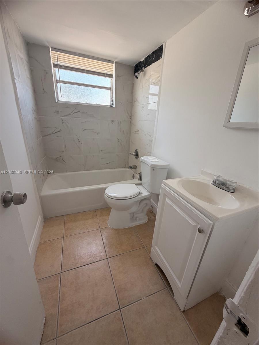 A small bathroom features a white vanity, a toilet, and a tiled bathtub shower combination — 8450 NE Miami Ct # 4, Miami FL 33138, MIAMI, FL
