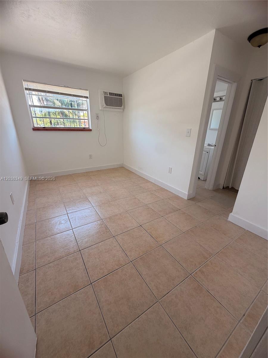A small, empty room features beige tile flooring, white walls, and a window air conditioner — 8450 NE Miami Ct # 4, Miami FL 33138, MIAMI, FL