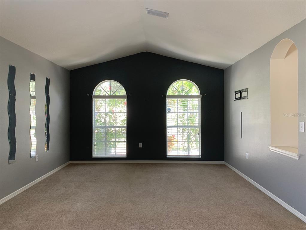 A living room features gray walls, a dark accent wall, vaulted ceilings, and arched windows — 11355 FLORA SPRINGS DRIVE, RIVERVIEW, FL