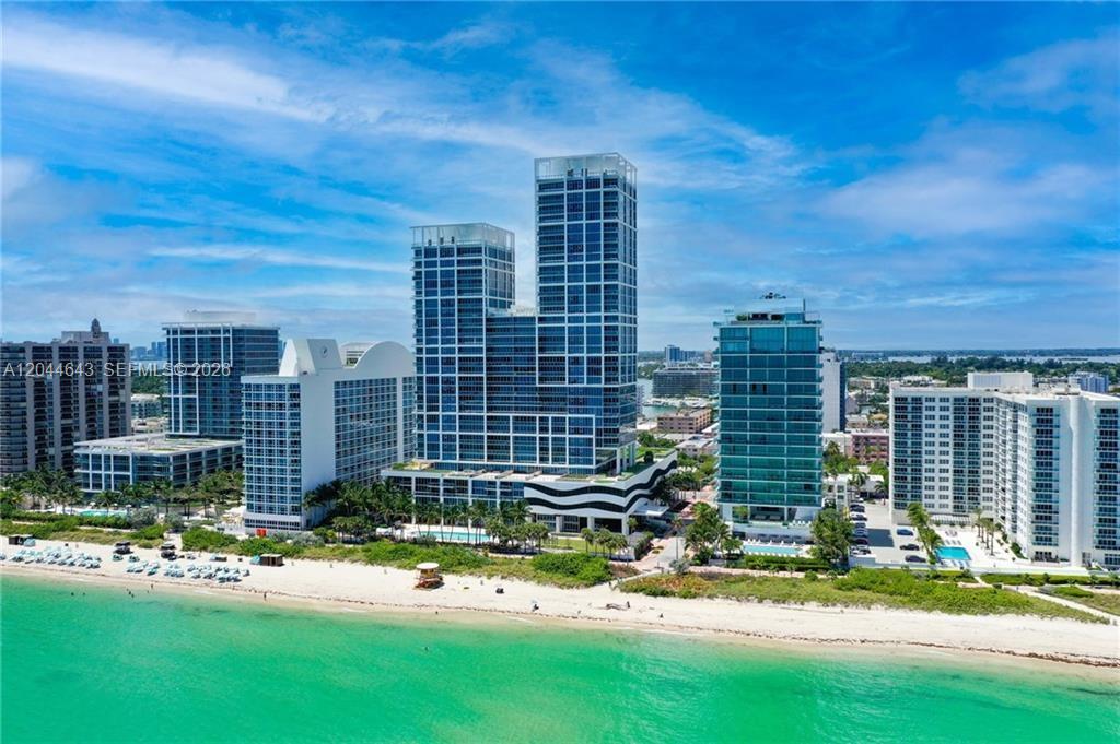 An aerial view shows several modern high-rise buildings situated directly along a sandy beach — 6899 Collins Ave # 2208, Miami Beach FL 33141, MIAMI BEACH, FL