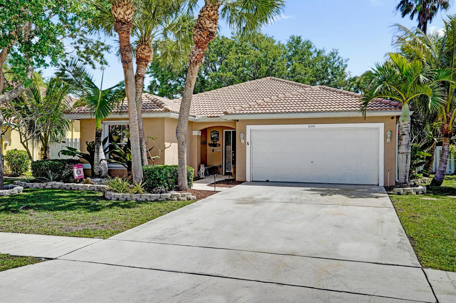 A single-story house with a beige stucco exterior, a tiled roof, and a two-car garage — 6214 Sand Hills Circle, Lake Worth FL 33463, LAKE WORTH, FL