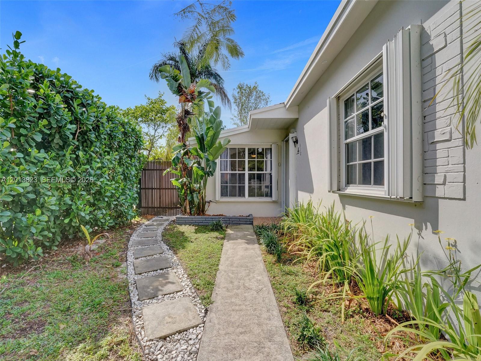 A concrete walkway leads to the entrance of a house with a stone path — 918 NE 4th Court, Hallandale Beach FL 33009, HALLANDALE BEACH, FL