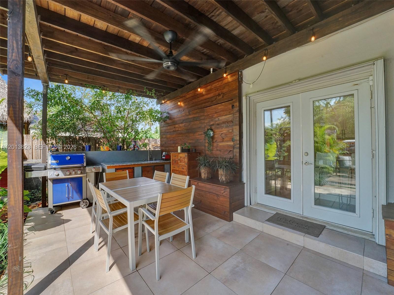 A covered patio features a dining set, outdoor kitchen, and wooden accent wall — 918 NE 4th Court, Hallandale Beach FL 33009, HALLANDALE BEACH, FL