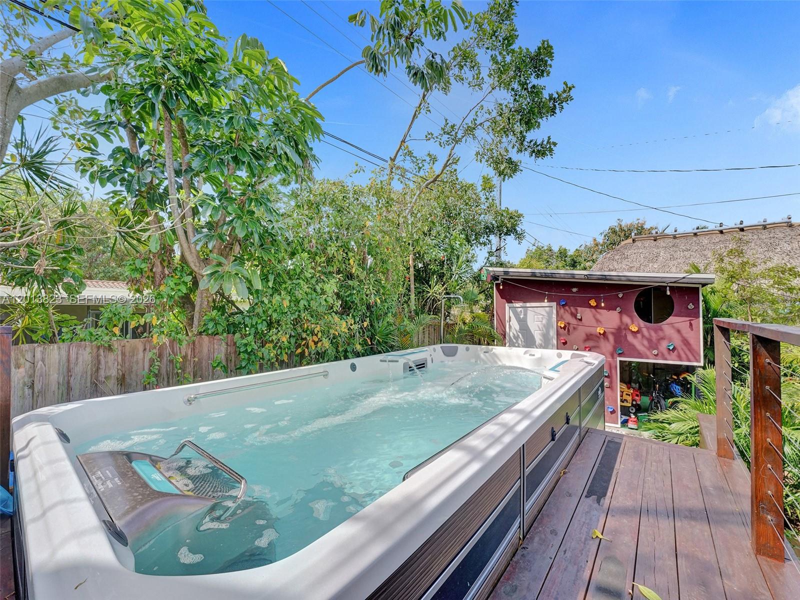 An outdoor swim spa sits on a wooden deck next to a small climbing wall structure — 918 NE 4th Court, Hallandale Beach FL 33009, HALLANDALE BEACH, FL