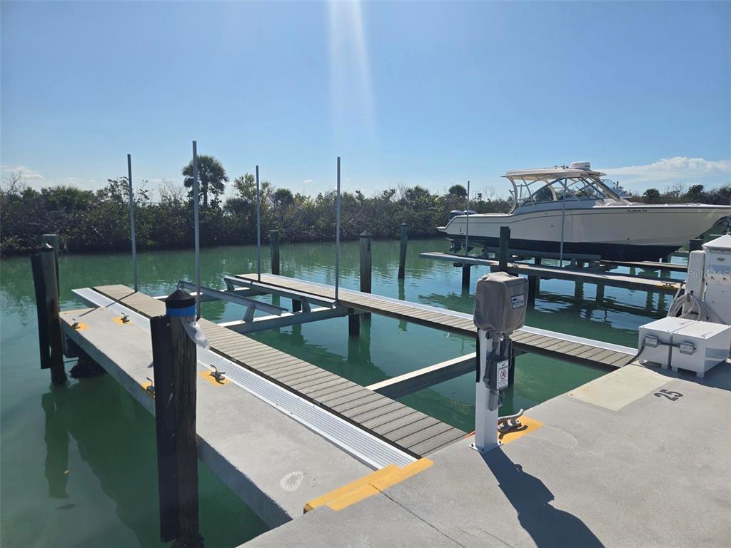 A boat slip with a mechanical lift and a concrete dock under a clear sky — 5820 GASPARILLA ROAD UNIT SLIP 25, BOCA GRANDE, FL