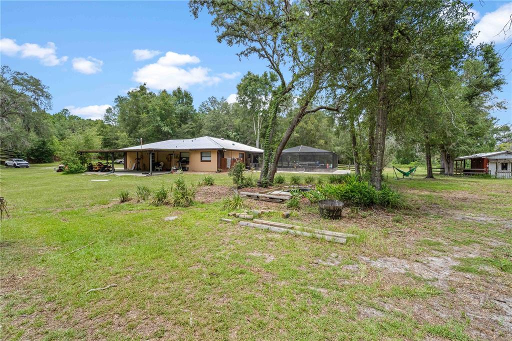 A single-story house with a covered patio and a screened pool sits on a lawn — 9459 N EUBANKS TERRACE, DUNNELLON, FL