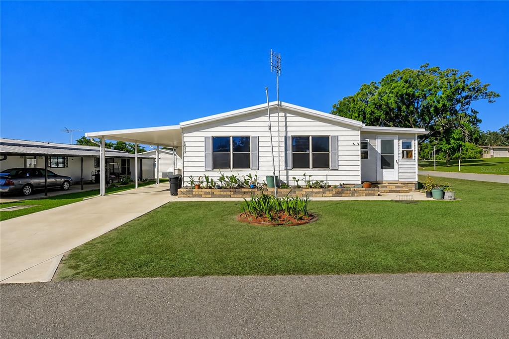 A white single-story manufactured home with a carport and a front lawn — 10151 HAMP DRIVE, DADE CITY, FL