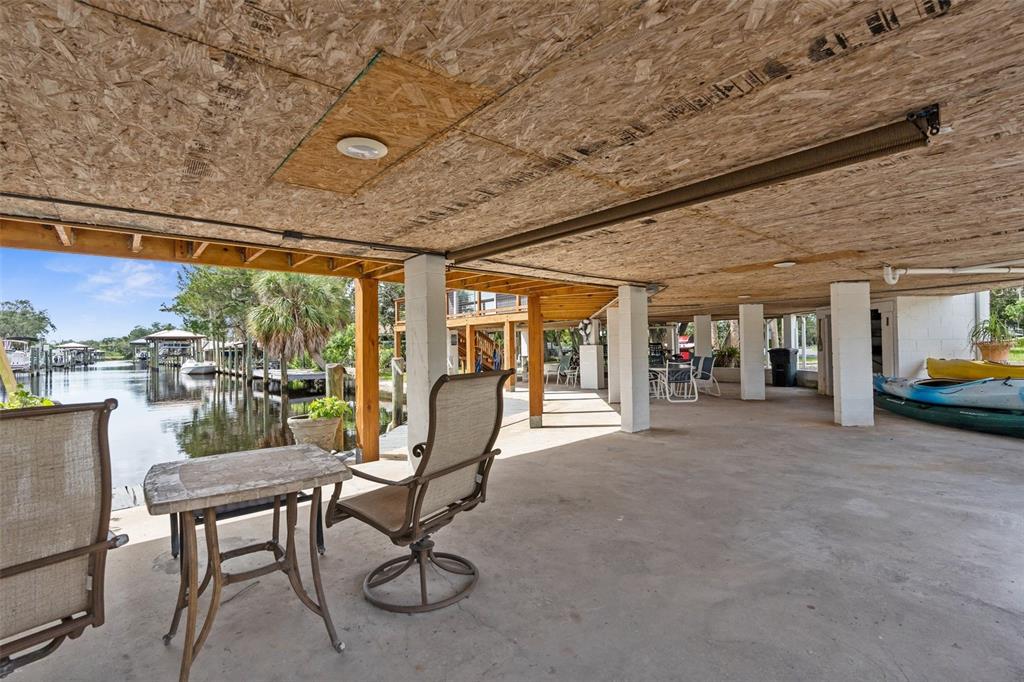 A covered concrete patio features exposed wood ceiling panels, support columns, and a waterfront view — 5648 S GARCIA ROAD, HOMOSASSA, FL