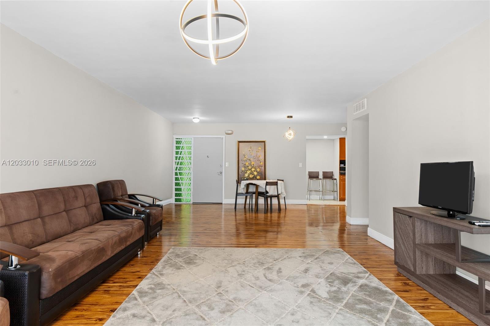 A living room features a brown sofa, a television on a stand, and hardwood floors — 1690 NE 191st St # 1, Miami FL 33179, MIAMI, FL