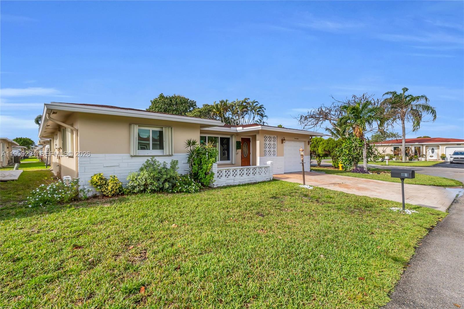 A single-story house features a beige and white exterior with a front lawn and driveway — 1280 NW 49th St, Deerfield Beach FL 33064, DEERFIELD BEACH, FL
