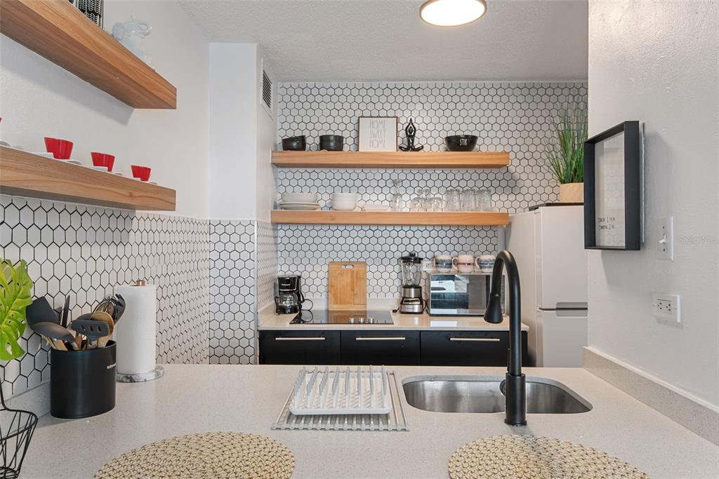 A kitchen features black cabinets, light countertops, open wood shelving, and white hexagonal tile backsplashes — 1404 COND PLAYA AZUL III UNIT 1404, LUQUILLO, PR