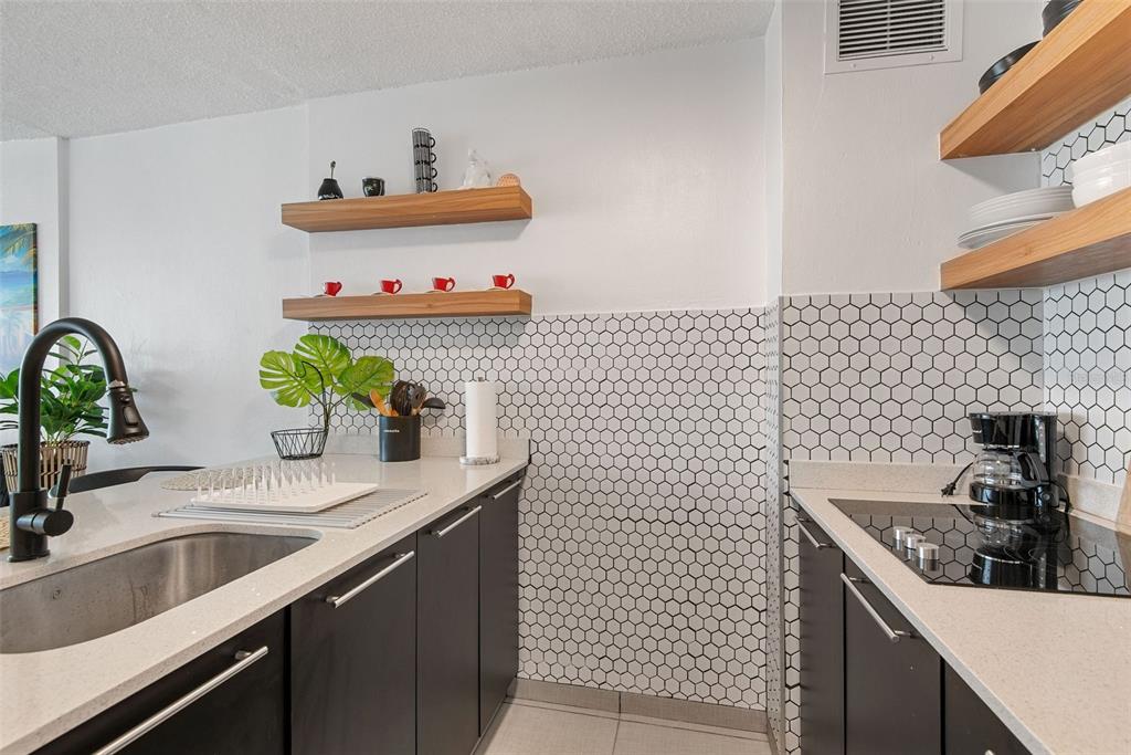 A kitchen features dark cabinets, light countertops, open wood shelving, and a white hexagonal backsplash — 1404 COND PLAYA AZUL III UNIT 1404, LUQUILLO, PR