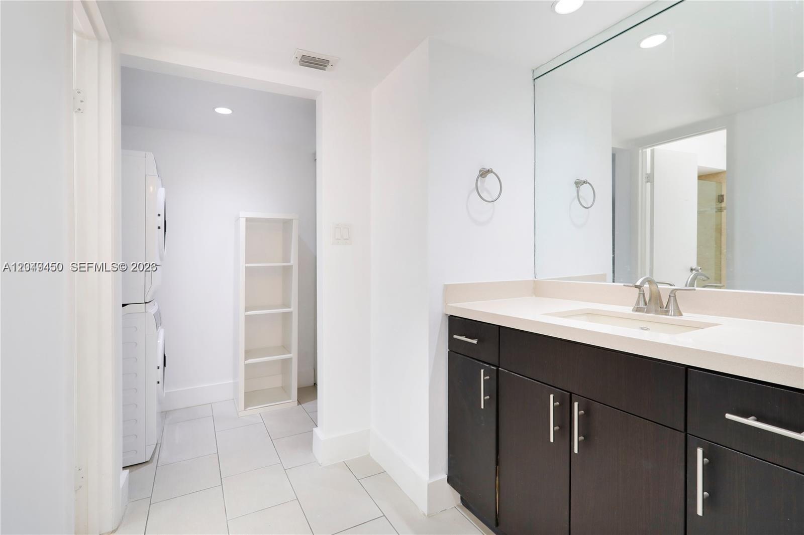 A bathroom features a dark wood vanity, a large mirror, and an adjacent laundry area — 8124 SW 87th Ter, Miami FL 33143, MIAMI, FL