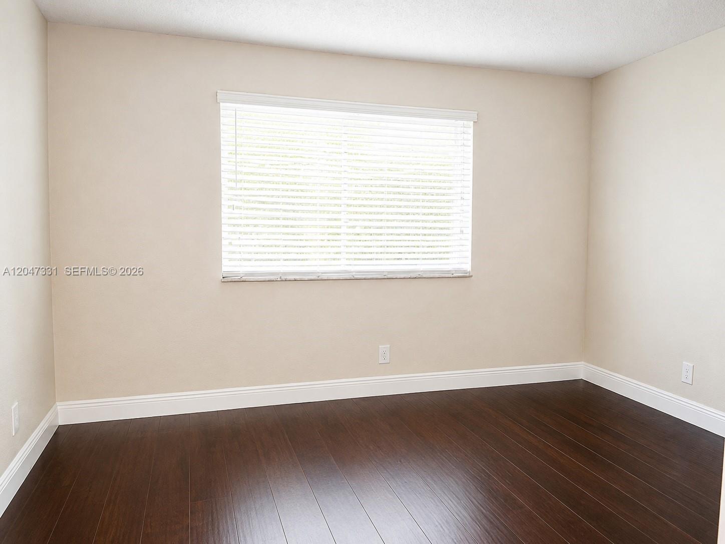 An empty room features dark wood flooring, beige walls, and a window with white blinds — 331 Lakeview Dr # 203, Weston FL 33326, WESTON, FL