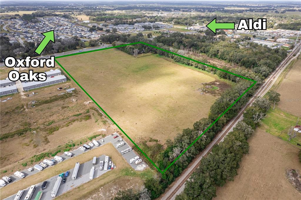 This aerial view shows a large, vacant, rectangular plot of land outlined in green — 11425 N US HIGHWAY 301, OXFORD, FL